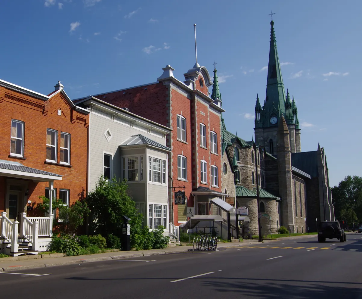 Rue résidentielle avec maisons colorées et église à Trois-Rivières en Mauricie